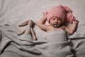 Cute newborn baby in warm hat sleeping on bedsheet, top view