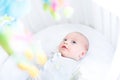 Cute newborn baby watching toys in his white crib Royalty Free Stock Photo
