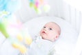 Cute newborn baby watching toys in his white crib