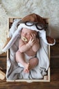 Cute newborn baby wearing aviator hat with toy sleeping in wooden crate Royalty Free Stock Photo