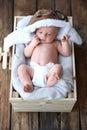 Cute newborn baby wearing aviator hat in crate, top view