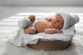 Cute newborn baby wearing warm hat and socks sleeping in wicker basket Royalty Free Stock Photo