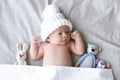 Cute newborn baby wearing white knitted hat with toys in bed Royalty Free Stock Photo