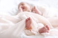 Cute newborn baby in white soft blanket after bath. Closeup of infant foot and blur pastel background Royalty Free Stock Photo