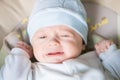 Cute nice little baby boy crying lying  on bed at home. Royalty Free Stock Photo