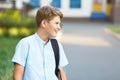 Cute, nice, young 11 years old boy in blue shirt stands with workbooks and backpack in front of his school. Education Royalty Free Stock Photo