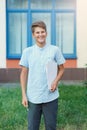 Cute, nice, young 11 years old boy in blue shirt stands with workbooks in front of his school. Education, back to school Royalty Free Stock Photo