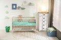 Cute nursery interior with comfortable crib near wall Royalty Free Stock Photo
