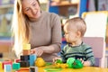 Cute nursery teacher and child toddler playing educational toys in kindergarten