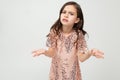 Cute offended teenager girl shiny dress indignant on a white studio background