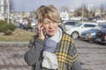 A cute older woman in casual clothes is talking on the phone on a city street in the spring Royalty Free Stock Photo