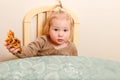 cute one-and-a-half-year-old girl with a ponytail on top of her holding a pancake sitting at table Royalty Free Stock Photo