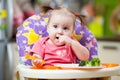 Cute one year old baby girl in highchair with pasta in kitchen at home Royalty Free Stock Photo