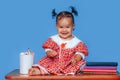 Cute one year old mixed race Asian Caucasian german girl wearing red dress smiles sweetly looking at the camera on blue background Royalty Free Stock Photo