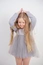 Cute orphan girl stands and holds her hands over her head in the form of a house, dreaming of an apartment, on a white background