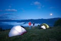 Cute pair is standing near camping holding hands against the backdrop of morning mountain scenery