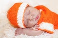 Cute peaceful sleeping newborn baby dressed in a knitted orange Royalty Free Stock Photo