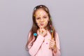 Cute pensive girl with her toothbrush standing isolated over gray background with toothbrush in hands, holding chin, thinking, Royalty Free Stock Photo