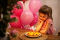 Cute pensive little girl looking at her birthday cake Royalty Free Stock Photo