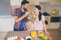 Cute picture of man standing at table and holding bowl with salad. He is stretching hand with wooden spoon with tomato Royalty Free Stock Photo