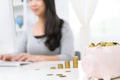 Cute piggy bank with gold coin and blur Woman working on computer at home office background. . concept saving money for finance