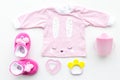 Cute pink baby clothes for girl. Shirt, booties, toy, bottle on white background top view copy space Royalty Free Stock Photo