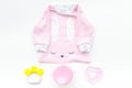 Cute pink baby clothes for girl. Shirt, toy, bottle on white background top view copy space Royalty Free Stock Photo