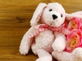 Cute pink dog doll and artificial rose flower decoration on wooden background Royalty Free Stock Photo