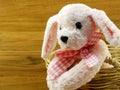 Cute pink dog doll in the basket with wooden background Royalty Free Stock Photo