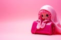 Cute pink doll keychain for bag on pink background