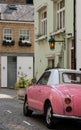 Cute pink Nissan Figaro retro style car, parked in a mews street in Queen`s Gate, Kensington, London UK. Royalty Free Stock Photo