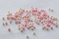 Cute pink and white beads are scattered on a white background, a festive pattern for a close-up wedding design. Hobby, craft and Royalty Free Stock Photo