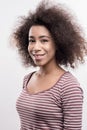 Cute pleasant curly dark-haired woman wearing striped plain shirt