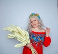 Cute plump girl from the village in a red summer sundress with a sheaf of wheat in her hands on white studio solid background