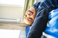 A Cute portrait of child upside down, lying on bed, smiling at camera and playing with toy