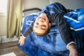 A Cute portrait of child upside down, lying on bed, smiling at camera and playing with toy