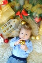 Cute portrait of little baby celebrates Christmas. New Year`s holidays. Boy in boytie lies under the tree, playing decoraction Royalty Free Stock Photo