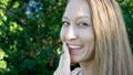 Cute portrait of young blonde woman face smoking daisy flower weed smiling with blue clear eyes isolated in nature Royalty Free Stock Photo