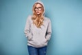 Cute positive blonde woman in gray hoodie and glasses