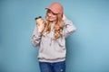 Cute positive blonde woman in pink cap with coffee
