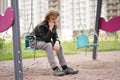 Cute positive boy teenager on the Playground in the city alone