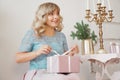 Cute positive woman near Christmas tree, opening gift Royalty Free Stock Photo