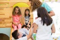 Cute girls smiling during playtime supervised by a young teacher Royalty Free Stock Photo