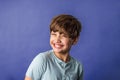 A cute pre-teen tween boy from the shoulders up on a blue purple backdrop