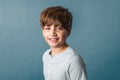 A cute pre-teen tween boy from the shoulders up on a muted blue backdrop