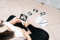 A cute pregnant belly and x ray ultrasound scan of baby. asian young pregnant female relax in the room looking at her child Royalty Free Stock Photo