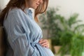 A cute pregnant woman sits in bed. The concept of a happy pregnancy. 9 months of waiting for a baby.