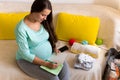 Cute Pregnant Woman writing packing list for maternity hospital With Notebook Prepares bags. Young Ledy In Pregnancy Royalty Free Stock Photo