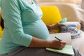 Cute Pregnant Woman writing packing list for maternity hospital With Notebook Prepares bags. Young Ledy In Pregnancy Royalty Free Stock Photo
