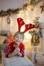 Cute preschool child, blond boy with pet dog, playing in decorated Christmas room Royalty Free Stock Photo